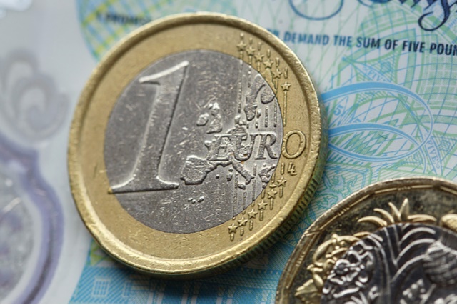 Pound and Euro coins on a five-Pound note.